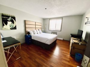 Hotel room with queen bed, ArtDeco desk and artwork, laminate flooring