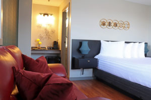 Nouveau room with a red couch, queen bed, ArtDeco accents